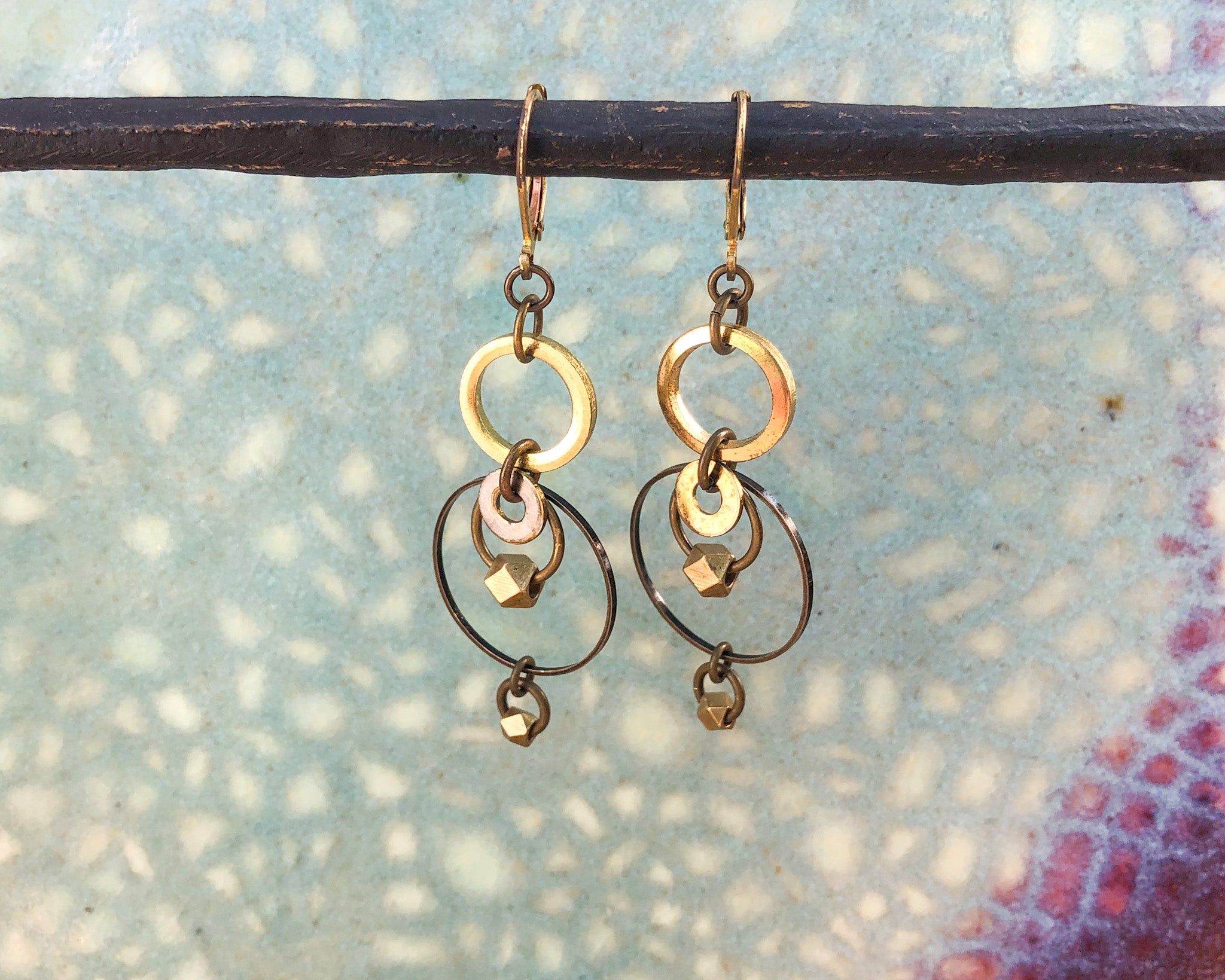 Brass concentric circles drop earrings on colored background