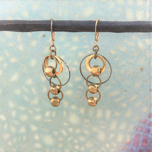 brass dangle earrings with smooth brass beads on colored background