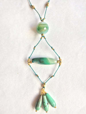 close-up of handmade necklace with green stones and nylon chord