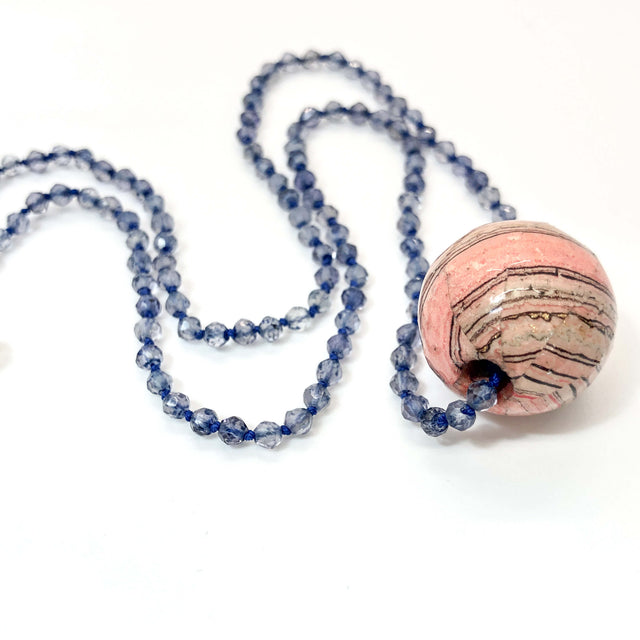 closeup of knotted iolite necklace with pink marbled paper bead charm