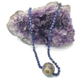 knotted sodalite bead necklace with handmade bead charm shown draped over crystal