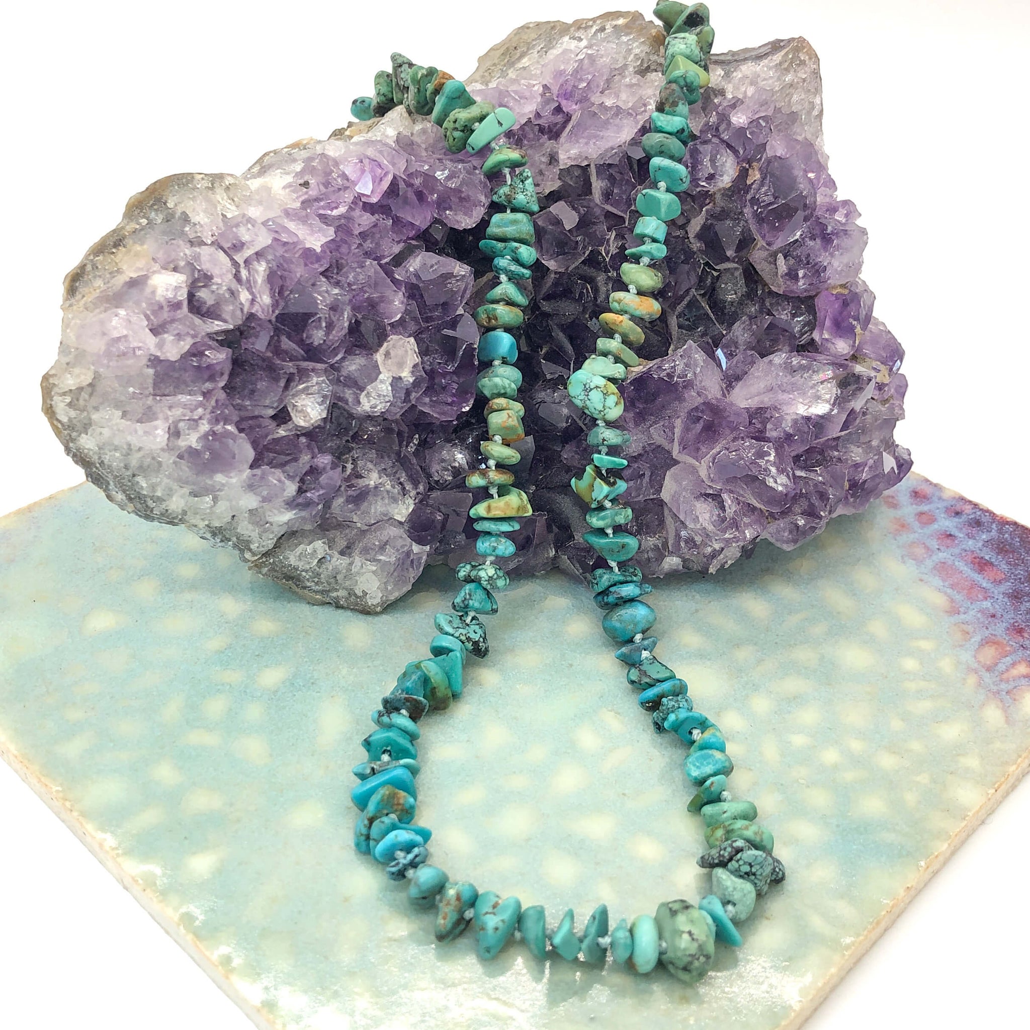 hand knotted turquoise nugget necklace displayed over a crystal and ceramic tile