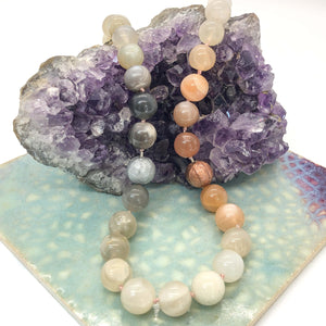 Hand knotted candy necklace with natural ombre moonstones and paper beads draped over crystal