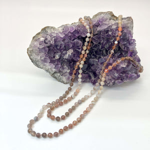knotted two strand ombre agate beaded necklace shown draped over a crystal