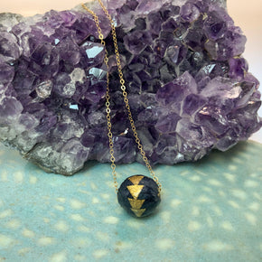 Navy and Gold Arrows Paper Bead Charm on Yellow Gold Filled Chain on model's neck on amethyst crystal