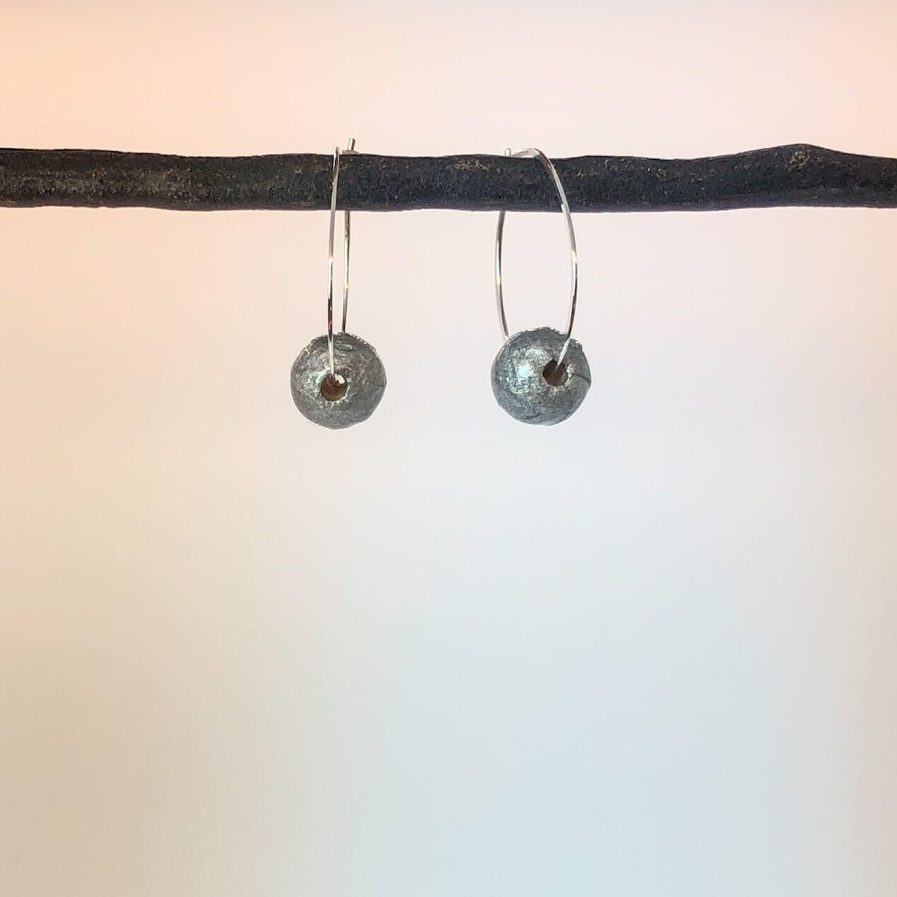 sterling silver hammered hoops with handmade silver paper bead shown on display